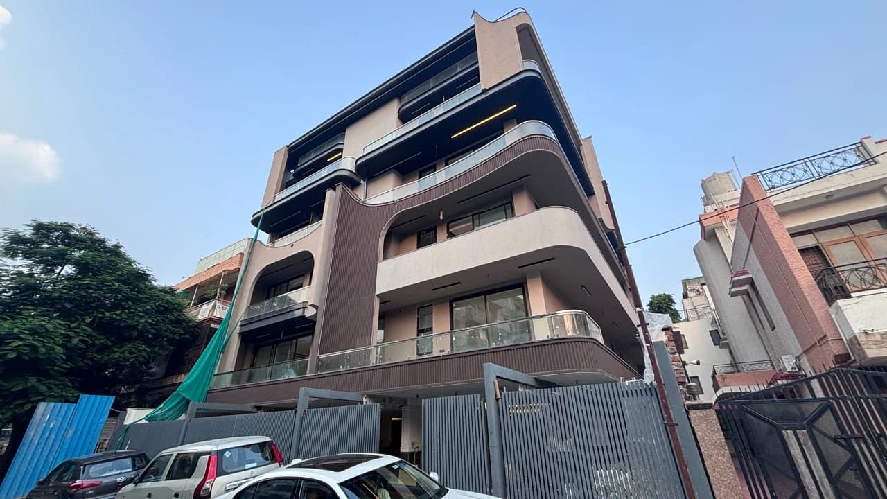 Sky Skrabers builder-floor facade with curved balconies, glass railings and a gated entrance